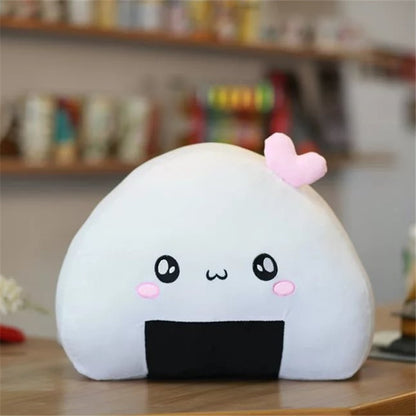 One white triangular plush onigiri pillow with black seaweed patch, kawaii face, pink cheeks and small pink...