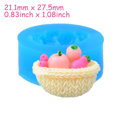 One blue round silicone mold behind a cream-colored woven basket holding five small pink and peach fruit sh...