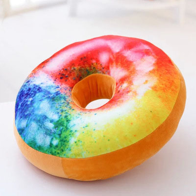 One round donut-shaped plush pillow with multicolor tie-dye top, tan sides and center hole.
