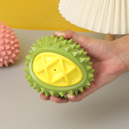 Hand holding one palm-sized green spiky oval toy with a yellow textured center and small hole.