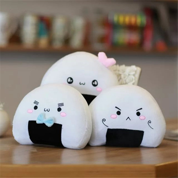 Three white rice-ball plushes with black seaweed patches and pink cheeks; blue and pink bows.
