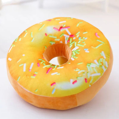 One round plush donut pillow with yellow-orange frosting, multicolored sprinkles and center hole.