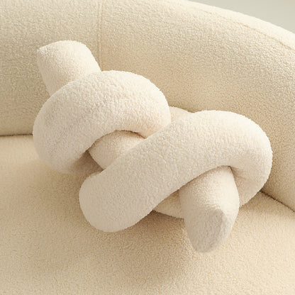 One cream-colored knotted tubular cushion with boucle texture on a matching sofa.