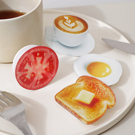 Fried egg, tomato and coffee phone grips on a breakfast plate