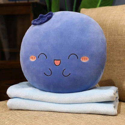Blueberry plush pillow sitting on its folded light blue blanket