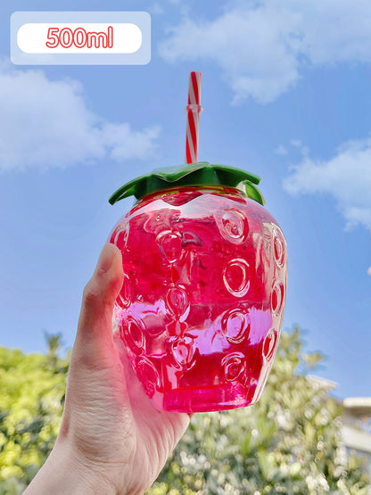 Hand holds one translucent pink strawberry 500ml bottle with green lid and red-white straw against blue sky.