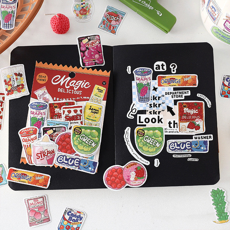 One open black notebook with a 'Magic Delicious' sticker sheet and many colorful food-themed stickers.