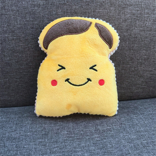 One yellow plush shaped like a smiling toast with brown top panels and red cheeks on a grey fabric couch.