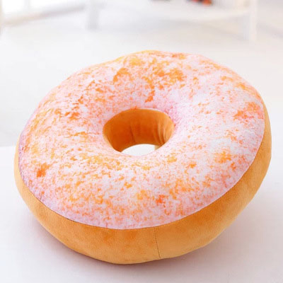 One round plush donut pillow with a pink speckled top, tan bottom, center hole, soft plush texture.