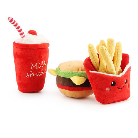 Three plush toys: red milkshake with striped straw, cheeseburger, and smiling red fries pack with yellow fr...