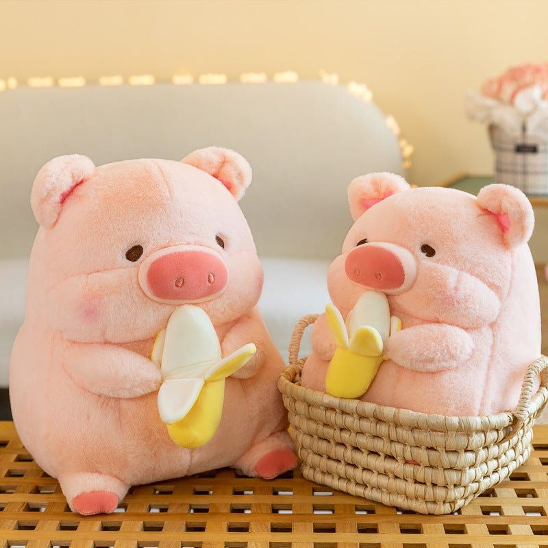Two adorable pink pig plush toys, one holding a banana, nestled in a wicker basket. Soft and cuddly with cheerful expressi...