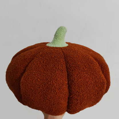 Chestnut brown teddy pumpkin plush cushion with a pale green stem held up by a hand