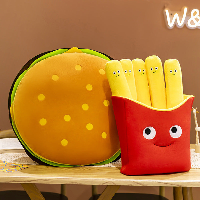 Two plush items: round burger pillow with yellow seeded bun and green lettuce, and a red fries box with fiv...