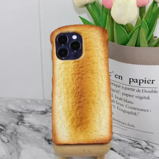 One toast-shaped phone case, golden-brown toasted texture, with square camera cutout revealing three lenses.