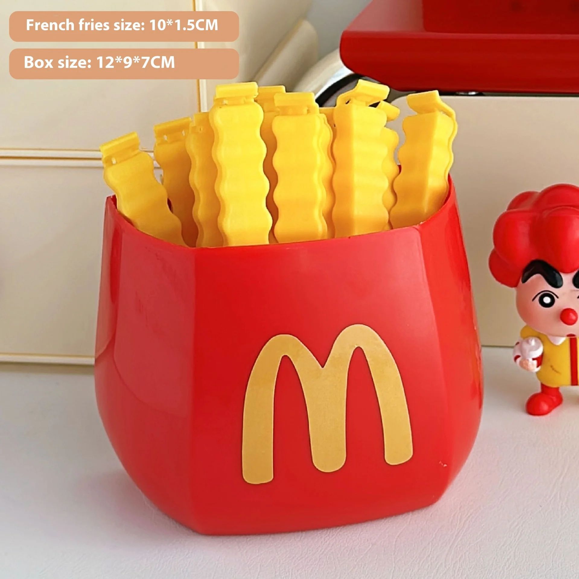 Red fries container with gold M logo holding nine yellow wavy bag clips and a small red-haired toy beside it.