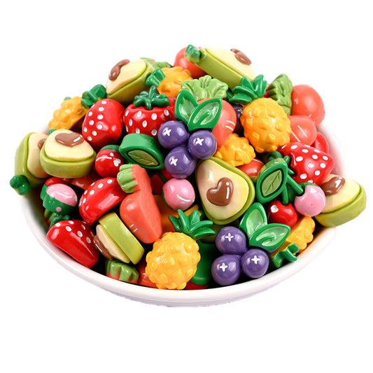 White bowl with about 40 glossy resin fruit charms: strawberries, avocados and pineapples.