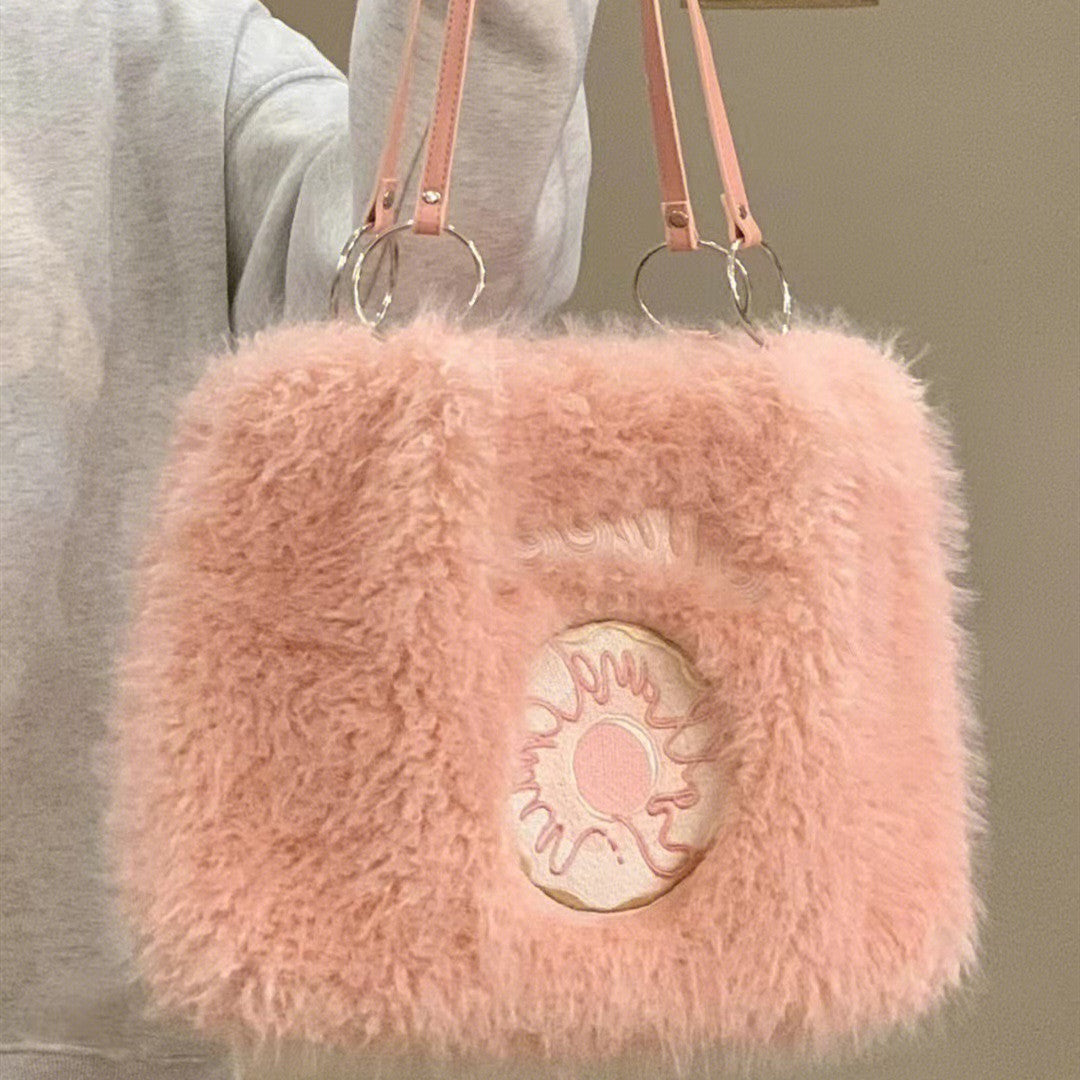 Pink fluffy tote bag with donut embroidery on the front, featuring two shoulder straps and metal rings, 30cm wide.