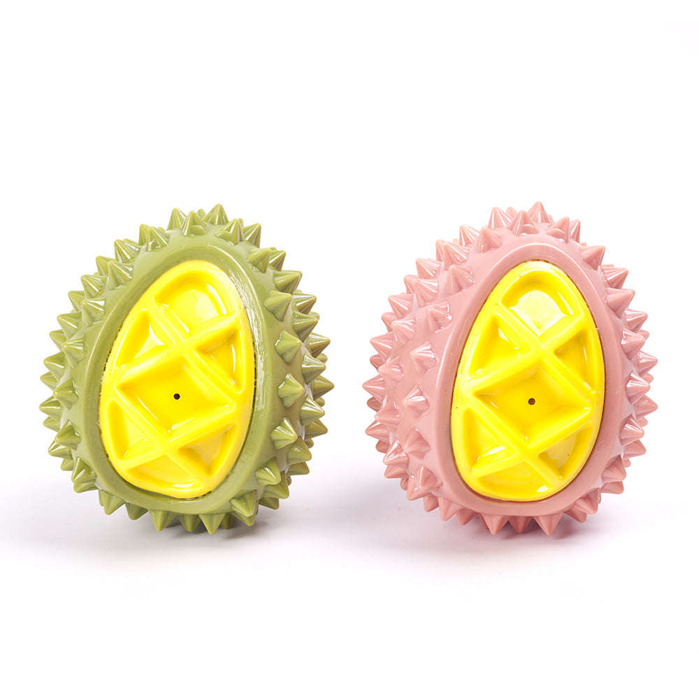 Two spiky oval dog chew toys, one olive green and one pink, each with a bright yellow grid-pattern center.