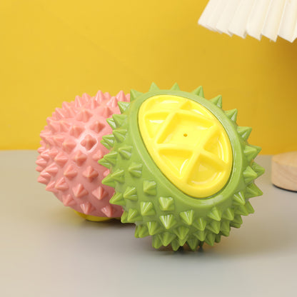 Two spiky rubber balls, one green with a yellow smooth oval center and one pink, on a gray surface.