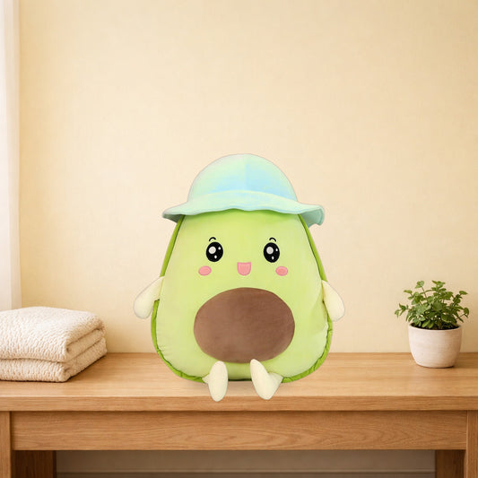 Green avocado plush toy with a blue bucket hat sitting on a light oak console table