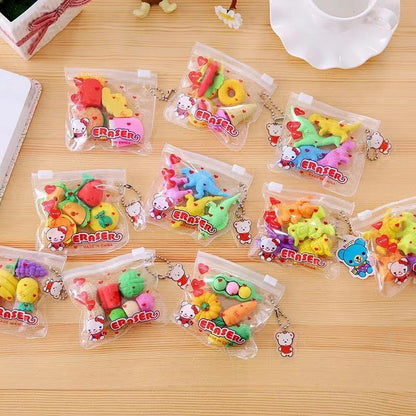 Eleven clear zipper keychain pouches holding assorted colorful food- and animal-shaped erasers on a light w...