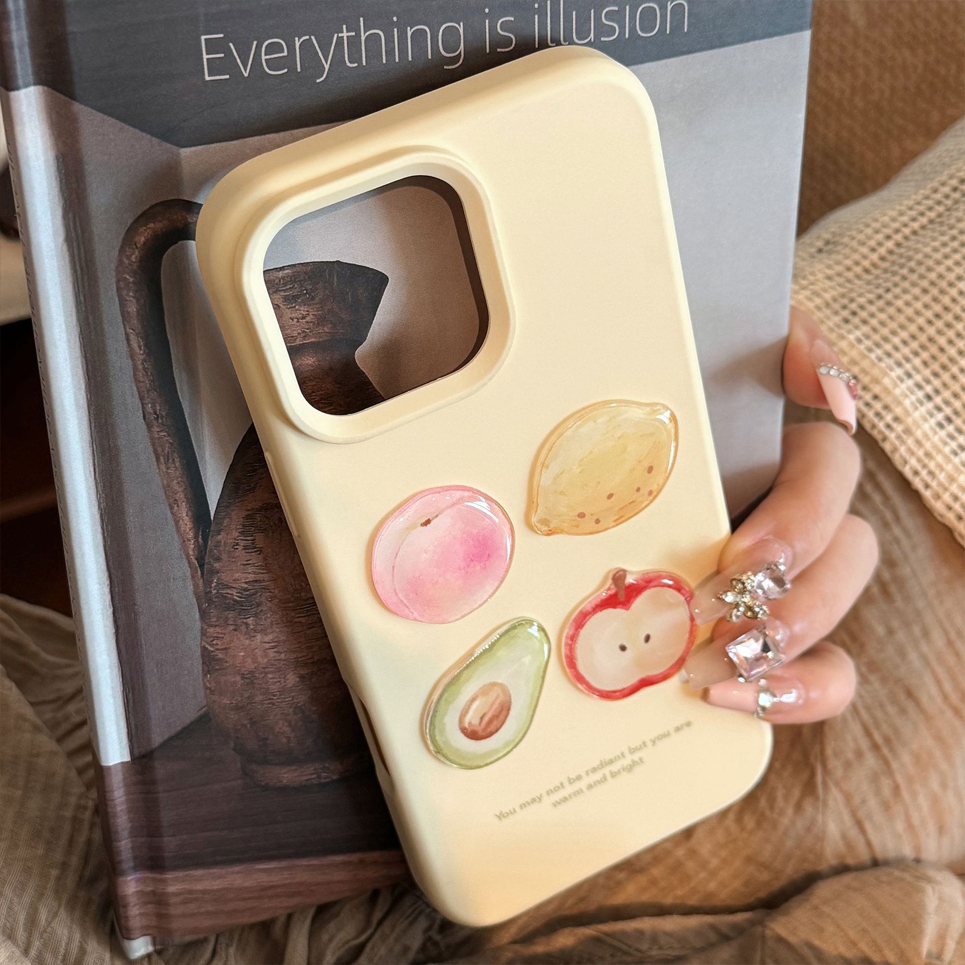 Cream iPhone case featuring 3D fruit designs: peach, apple, avocado, and lemon, adding a playful touch.