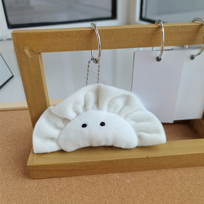 Dumpling plush keychain hanging on a stand