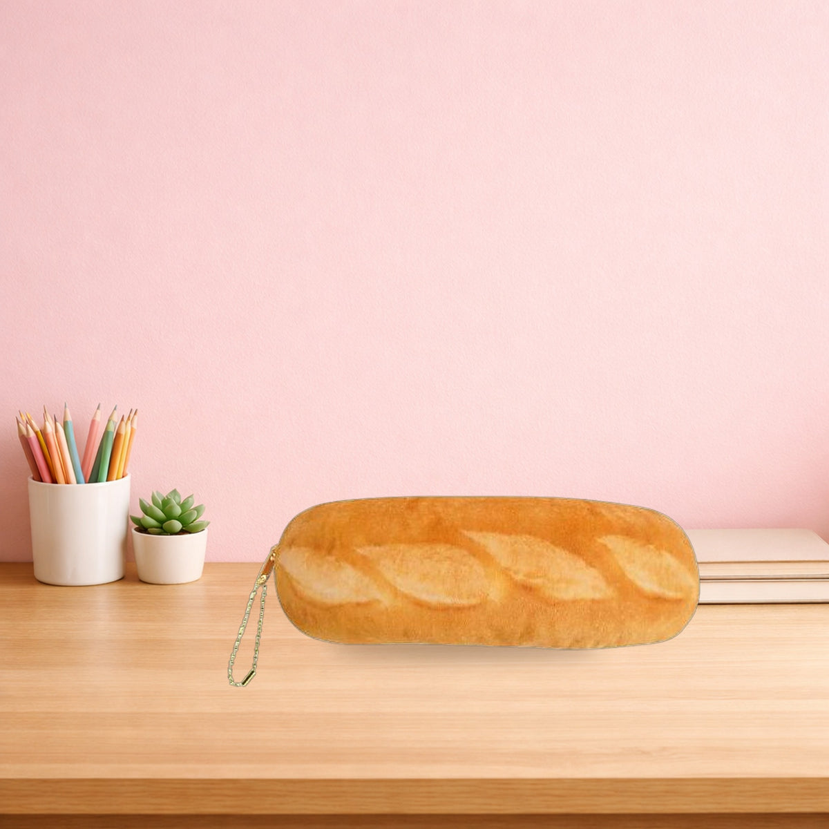 Baguette plush pencil case lying on a light oak desk beside a pot of pencils