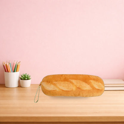 Baguette plush pencil case lying on a light oak desk beside a pot of pencils