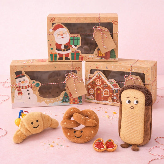 Bakery Bestie gift set with croissant and pretzel keyrings, toast pencil case and tart clips beside Christmas boxes