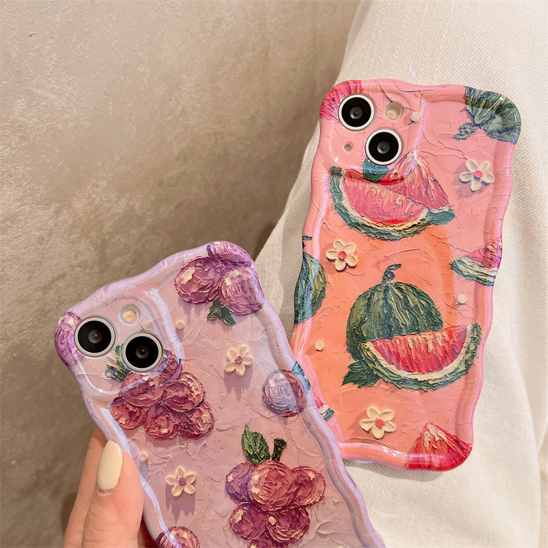 Two textured iPhone cases: one lilac with raised pink flowers, one coral-pink with watermelon slices.