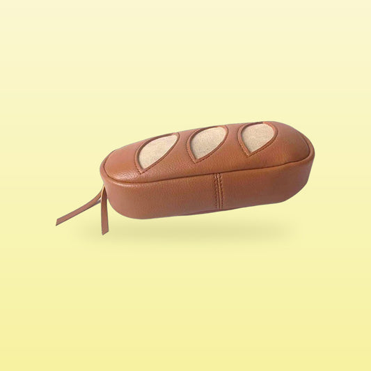 Tan baguette faux leather makeup bag with a zip pull, bag only, on a butter yellow background