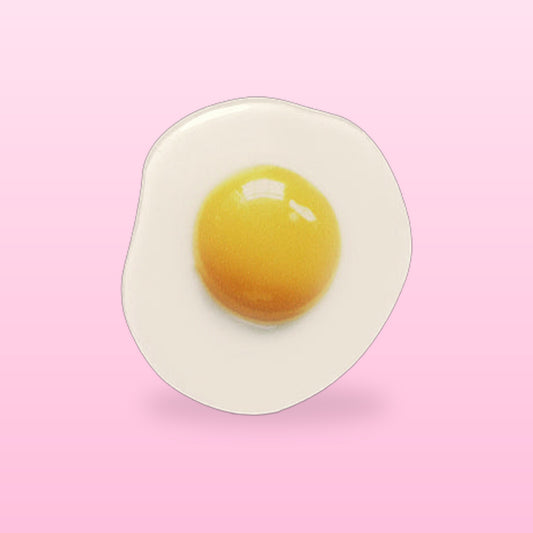 Fried egg phone grip with a glossy yellow yolk, on a pink background