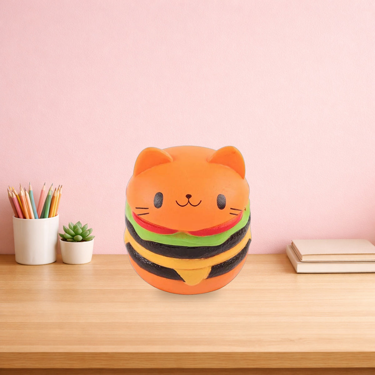 Cat face burger squishy sitting on a light oak desk beside pencils