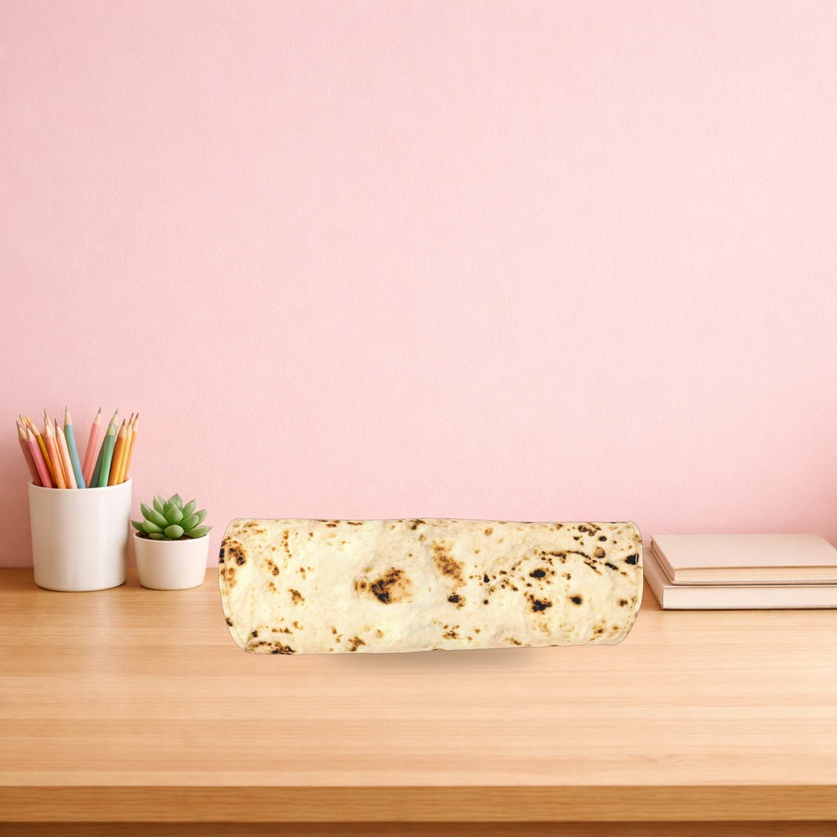 Burrito pencil case rolled up on a light oak desk