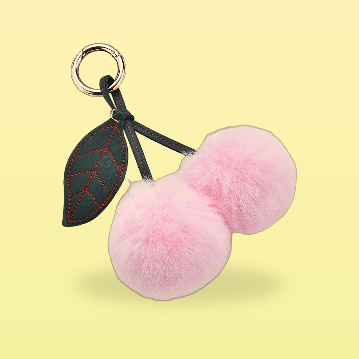 Fluffy baby pink pom-pom cherry bag charm with a dark green stitched leaf and gold clip