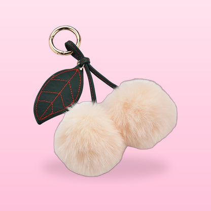 Fluffy cream pom-pom cherry bag charm with a dark green stitched leaf and gold clip