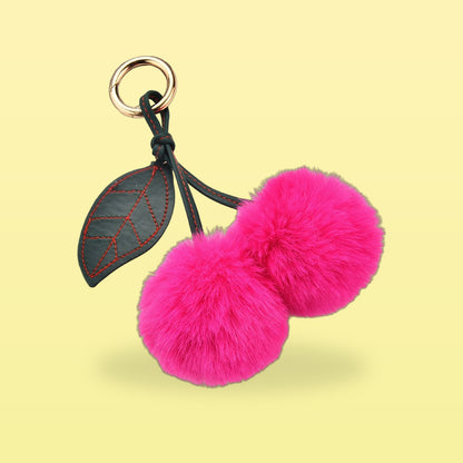 Fluffy hot pink pom-pom cherry bag charm with a dark green stitched leaf and gold clip