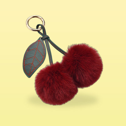 Fluffy wine red pom-pom cherry bag charm with a dark green stitched leaf and gold clip