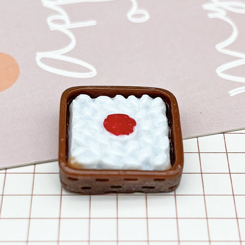 Small square brown tray with textured white filling and a red round center, placed on grid paper.