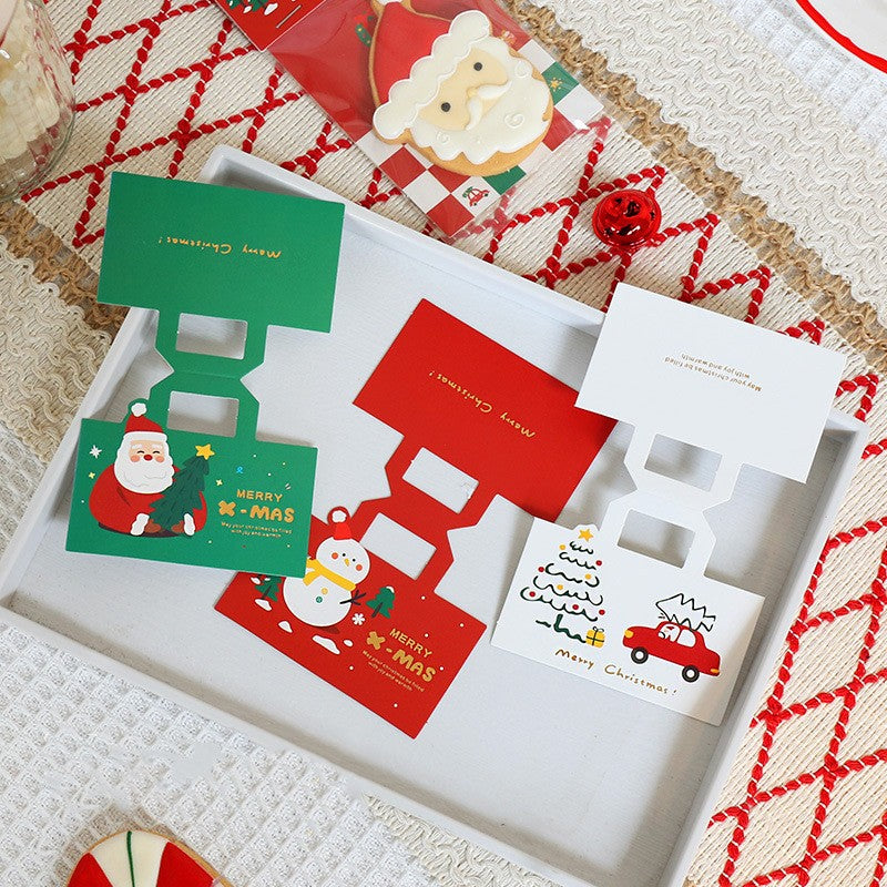 Colourful Christmas biscuit gift bags featuring Santa, a snowman, and a festive tree on a textured tablecloth.