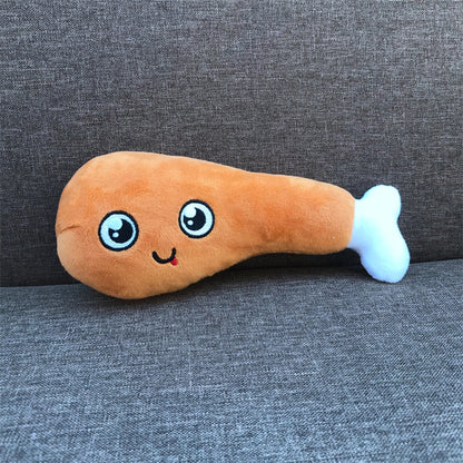 Brown plush drumstick with embroidered big eyes and smile and white bone tip, lying on gray fabric sofa.