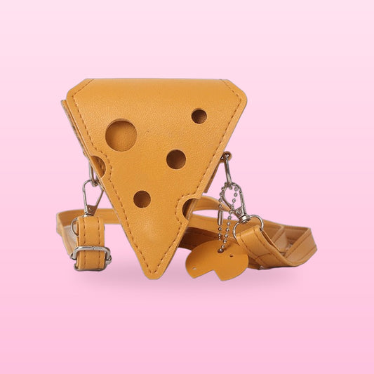 Mustard triangle cheese crossbody bag with holes, a cheese charm and a matching strap on a pink background