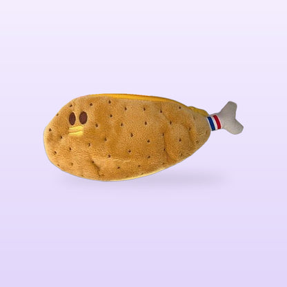 Chicken leg plush pencil case with a little face and striped bone end, on a soft lilac background