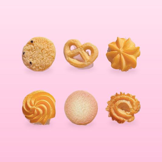 Six cookie hair clips: cranberry, pretzel, flower, swirl, butter and ring cookie, on a pink background