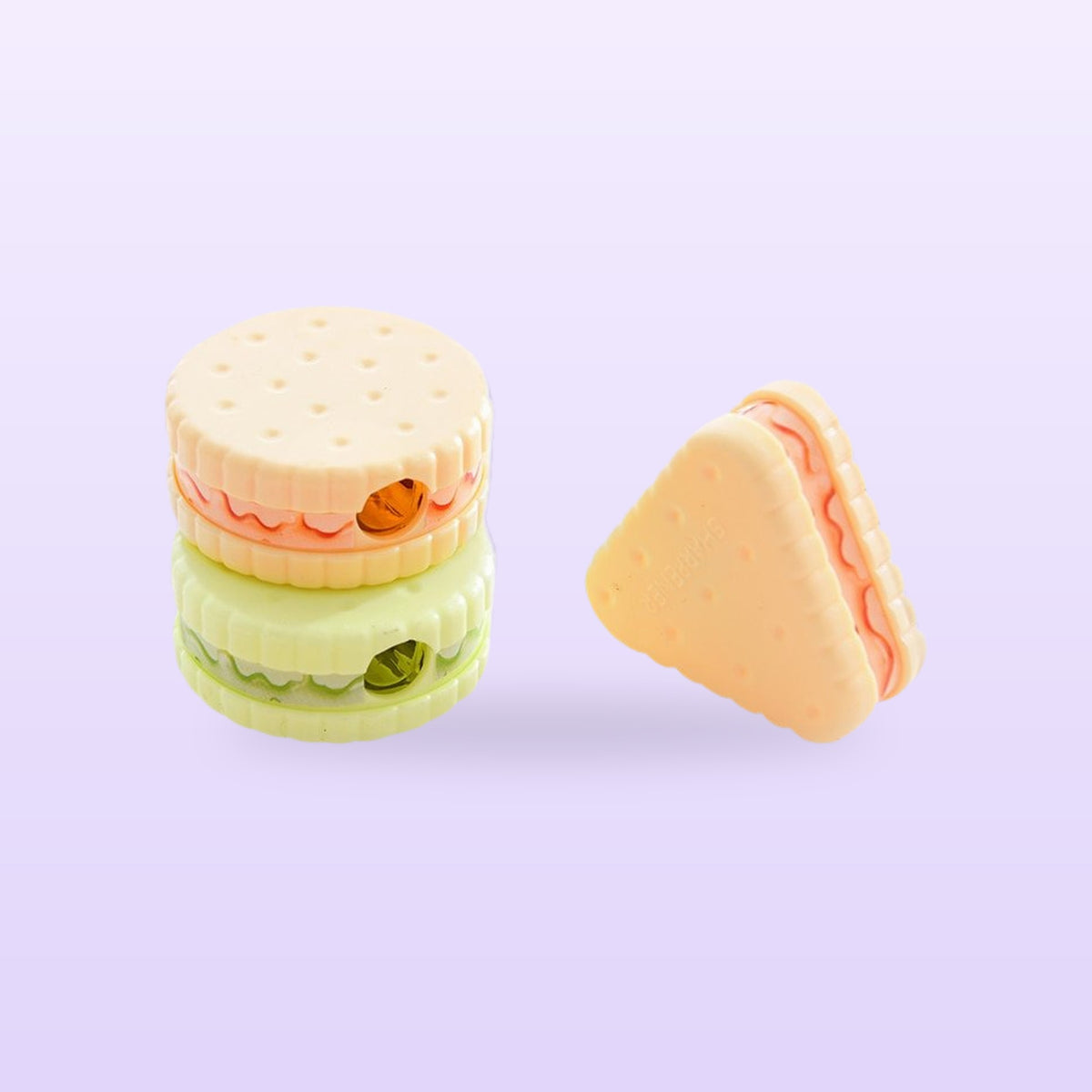 Cookie pencil sharpeners, two stacked round ones and a triangle, on a lilac background