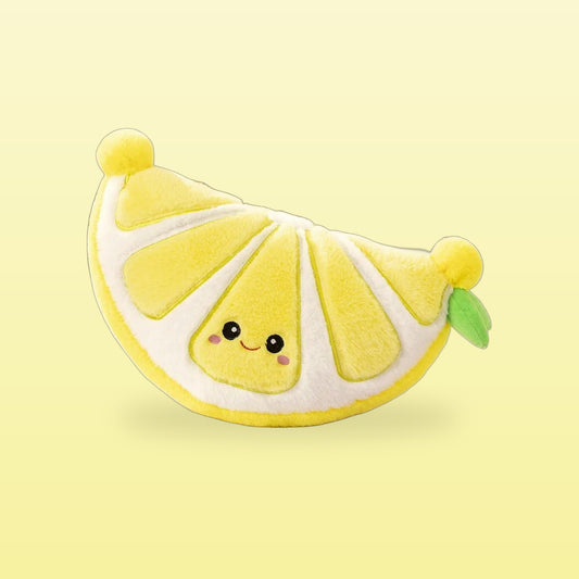 Smiling lemon slice plush with pompom ends and a green leaf on a butter yellow background