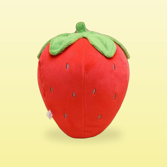 Red strawberry plush toy with a green leafy top, on a butter yellow background