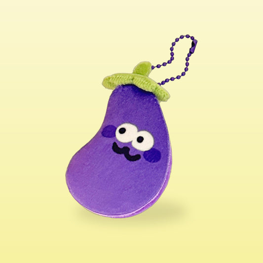 Eggplant plush keychain with a purple bead chain and a cheeky smile, on a butter yellow background