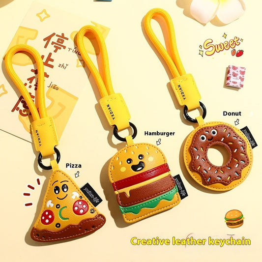 Three leather food keychains: smiling pizza slice, burger, and chocolate‑sprinkle donut with yellow loops.